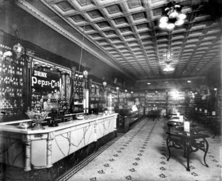 C. D. Bradham's drugstore in New Bern in the 1910s, with Pepsi-Cola advertisement painted on a mirror behind the soda fountain. Photograph by Bayard Wootten. North Carolina Collection, University of North Carolina at Chapel Hill Library.