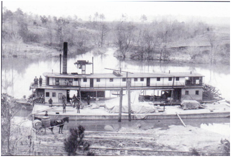 A large two-level boat floating in the water surrounded by trees. There is a large chimney-like tower on the boat. The photo is black and white.